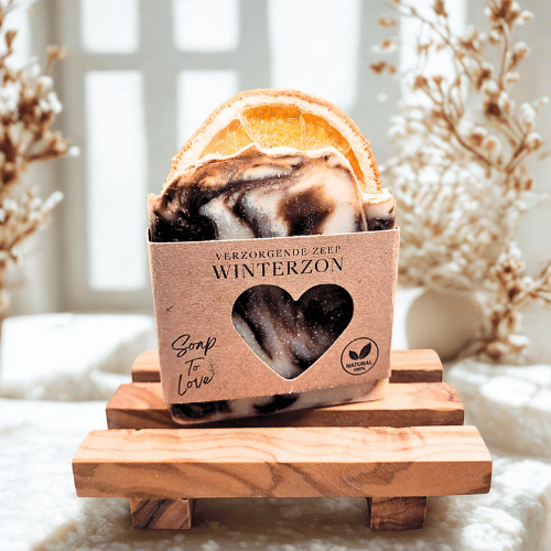 Bruin-witte gemarmerde winterzeep Winterzon met een gedroogd sinaasappelschijfje op een houten zeepbakje